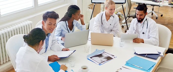 A group of medical professionals around a table discussing and looking at paperwork